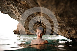 Beautiful young girl with redhead tied hair in the water cave
