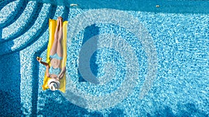 Beautiful young girl relaxing in swimming pool, swims on inflatable mattress and has fun in water on family vacation