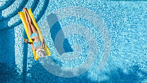 Beautiful young girl relaxing in swimming pool, swims on inflatable mattress and has fun in water on family vacation