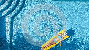 Beautiful young girl relaxing in swimming pool, swims on inflatable mattress and has fun in water on family vacation