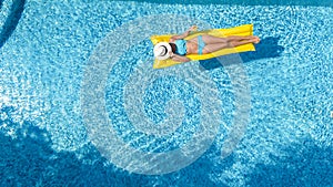 Beautiful young girl relaxing in swimming pool, swims on inflatable mattress and has fun in water on family vacation