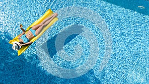 Beautiful young girl relaxing in swimming pool, swims on inflatable mattress and has fun in water on family vacation