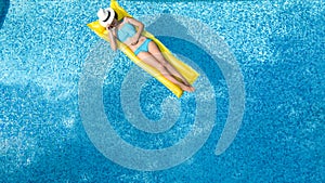 Beautiful young girl relaxing in swimming pool, swims on inflatable mattress and has fun in water on family vacation