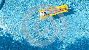 Beautiful young girl relaxing in swimming pool, swims on inflatable mattress and has fun in water on family vacation