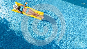 Beautiful young girl relaxing in swimming pool, swims on inflatable mattress and has fun in water on family vacation