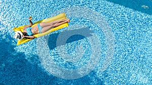 Beautiful young girl relaxing in swimming pool, swims on inflatable mattress and has fun in water on family vacation