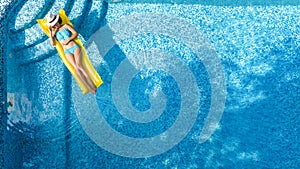 Beautiful young girl relaxing in swimming pool, swims on inflatable mattress and has fun in water on family vacation