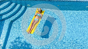 Beautiful young girl relaxing in swimming pool, swims on inflatable mattress and has fun in water on family vacation, aerial view