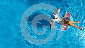 Beautiful young girl relaxing in swimming pool, swims on inflatable ring and has fun in water on family vacation