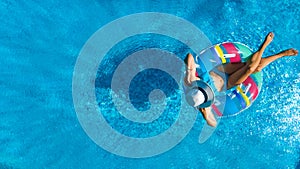 Beautiful young girl relaxing in swimming pool, swims on inflatable ring and has fun in water on family vacation