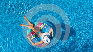 Beautiful young girl relaxing in swimming pool, swims on inflatable ring and has fun in water on family vacation