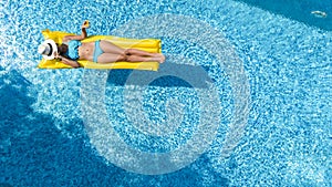 Beautiful young girl relaxing in swimming pool, woman swims on inflatable mattress and has fun in water on family vacation