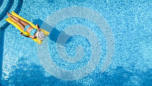 Beautiful young girl relaxing in swimming pool, woman swims on inflatable mattress and has fun in water on family vacation