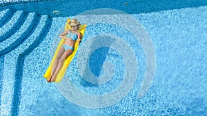 Beautiful young girl relaxing in swimming pool, woman swims on inflatable mattress and has fun in water on family vacation