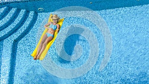 Beautiful young girl relaxing in swimming pool, woman swims on inflatable mattress and has fun in water on family vacation