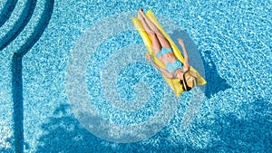 Beautiful young girl relaxing in swimming pool, woman swims on inflatable mattress and has fun in water on family vacation