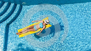 Beautiful young girl relaxing in swimming pool, woman swims on inflatable mattress and has fun in water on family vacation
