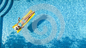 Beautiful young girl relaxing in swimming pool, woman swims on inflatable mattress and has fun in water on family vacation