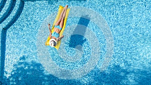 Beautiful young girl relaxing in swimming pool, woman swims on inflatable mattress and has fun in water on family vacation