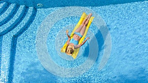 Beautiful young girl relaxing in swimming pool, woman swims on inflatable mattress and has fun in water on family vacation