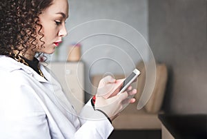 A beautiful young girl responds to a guy`s SMS. Close-up of a woman in a white shirt writing a message. A woman with red lips