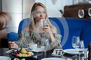 Beautiful young girl in restaurant with a glass in hands