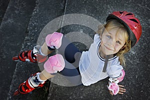 Beautiful young girl resting after rollerblading in the park