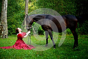 Beautiful young girl in retro dress posing near horse