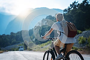 Beautiful young girl rides a bicycle on a beautiful mountain road. Summer holidays and cycling, sports and outdoor activities