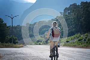 Beautiful young girl rides a bicycle on a beautiful mountain road. Summer holidays and cycling, sports and outdoor activities