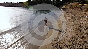 Beautiful young girl runs along the beach near the ocean