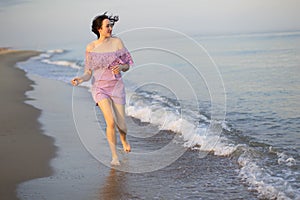 Beautiful young girl runs along the sea.