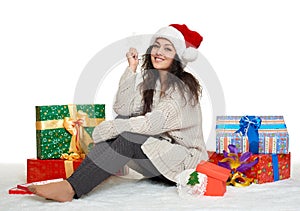 Beautiful young girl in santa hat with big snowflake toy and gift boxes, white background