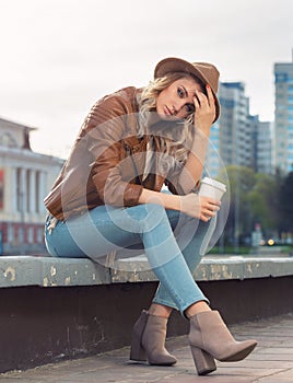 Beautiful young girl sat down on the curb