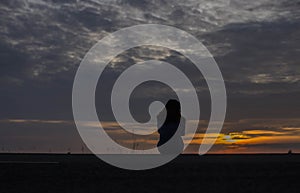 A beautiful young girl is showing the sunset in the water. photo