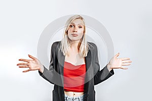 Beautiful young girl shrugs off her hands does not know what to decide on gray isolated background