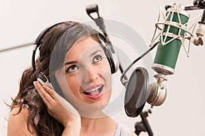 Beautiful young girl singing in music studio