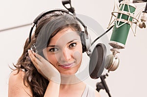 Beautiful young girl singing in music studio