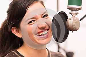 Beautiful young girl singing in music studio