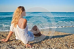 Beautiful young girl sit and look to the sea