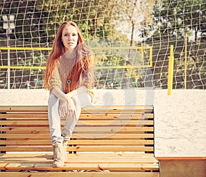 Beautiful young girl sitting on a bench on a warm summer day