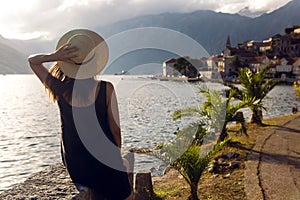 Beautiful young girl sitting in hat on the background of mountains and sea