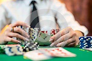 beautiful young girl is sitting at a poker table with cards in her hands.