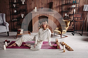 Beautiful young girl sitting relaxing on mat with candles in stylish cozy comfort home interior with comfy furniture