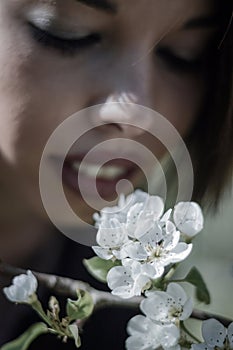 Beautiful young girl smelling a twig of blooming plum flowers