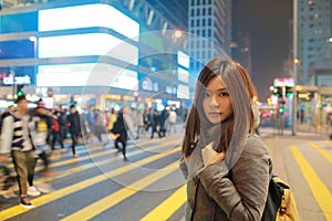 Beautiful young girl stand out and watching at night in hong kong, lost in city , busy crowd and yellow zebra crossing
