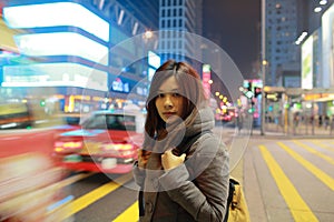 Beautiful young girl stand out and watching at night in hong kong, lost in city , busy crowd and yellow zebra crossing