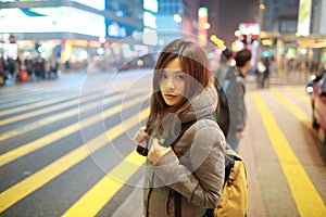 Beautiful young girl stand out and watching at night in hong kong, lost in city , busy crowd and yellow zebra crossing