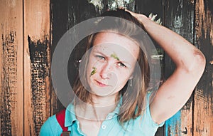 Beautiful and young girl standing on the background of painted wall paint. The girl`s face was stained with a green paint - she wa