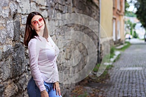 Beautiful young girl standing near the stone wall. Portrait pretty young fashion girl near a stone wall. Beautiful blonde woman